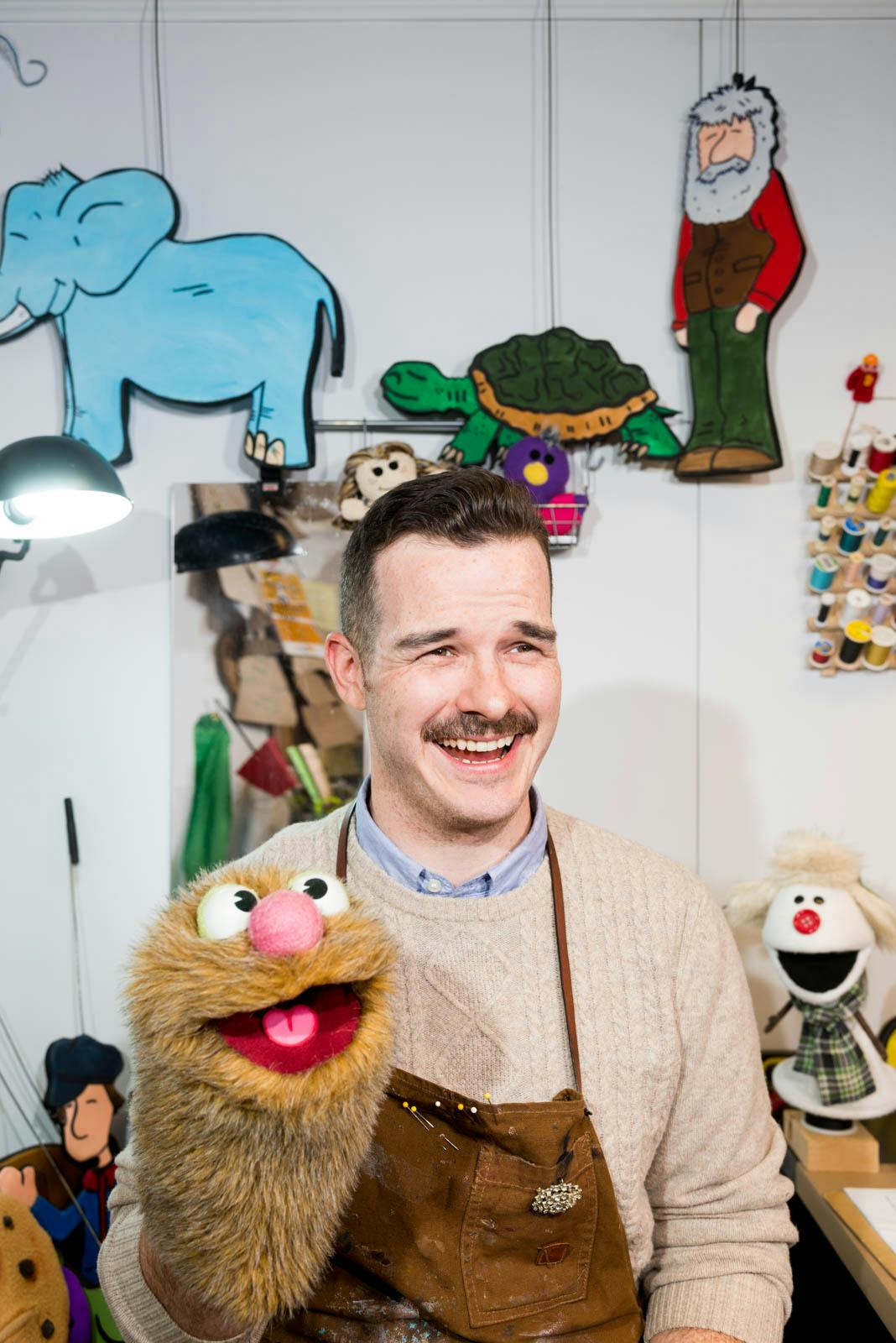 A puppeteer in his workshop holding one of his creations.